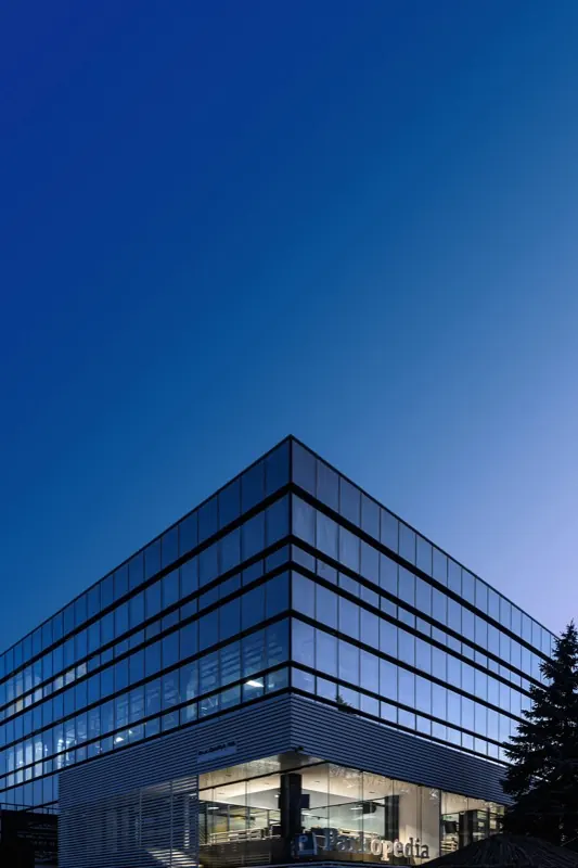 Modern glass office building at dusk where TransportPlus collects staff for the night shift